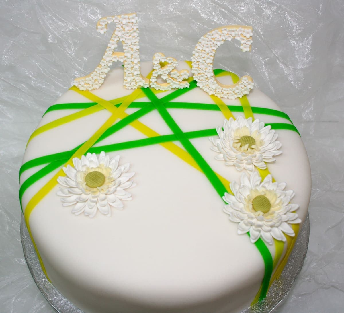 Moderne Hochzeitstorte mit Initialen und Gänseblümchen