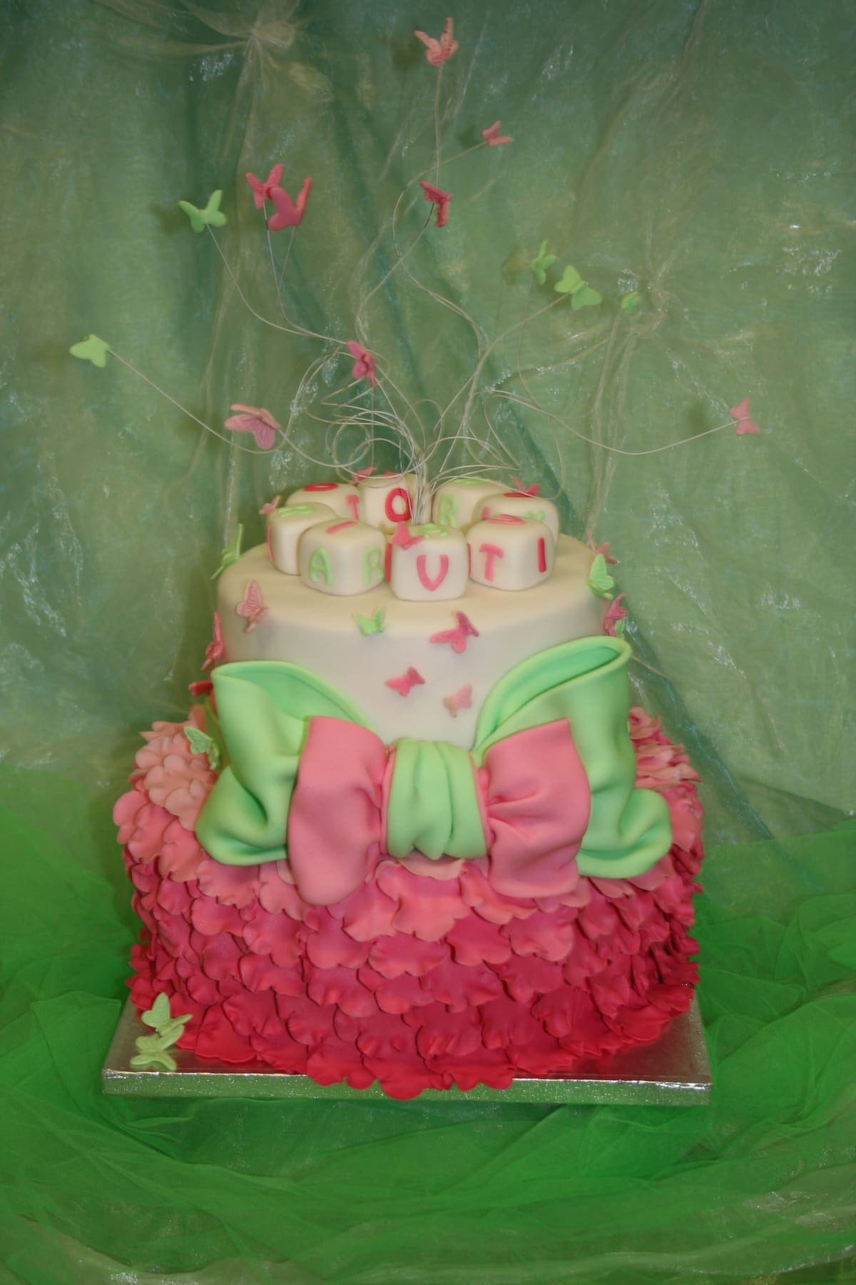 Rosa-grüne Torte mit Schmetterlingen und großer Schleife