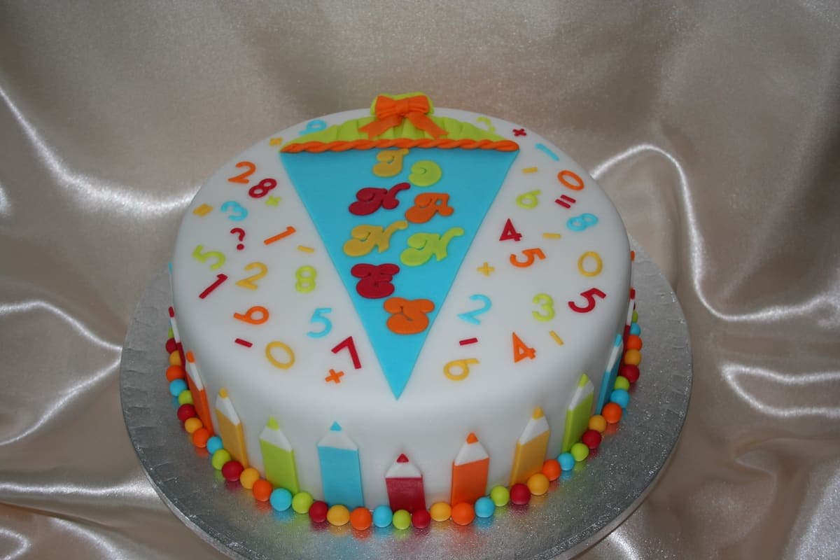 Bunte Einschulungstorte mit Zahlen, Buchstaben und Schultasche