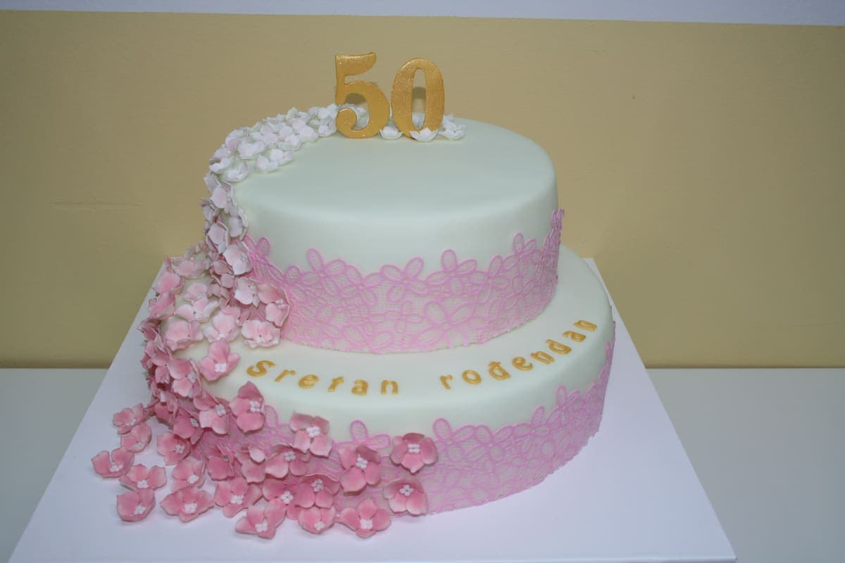 Elegante 50. Geburtstagstorte mit Spitze und rosa Blütenkaskade