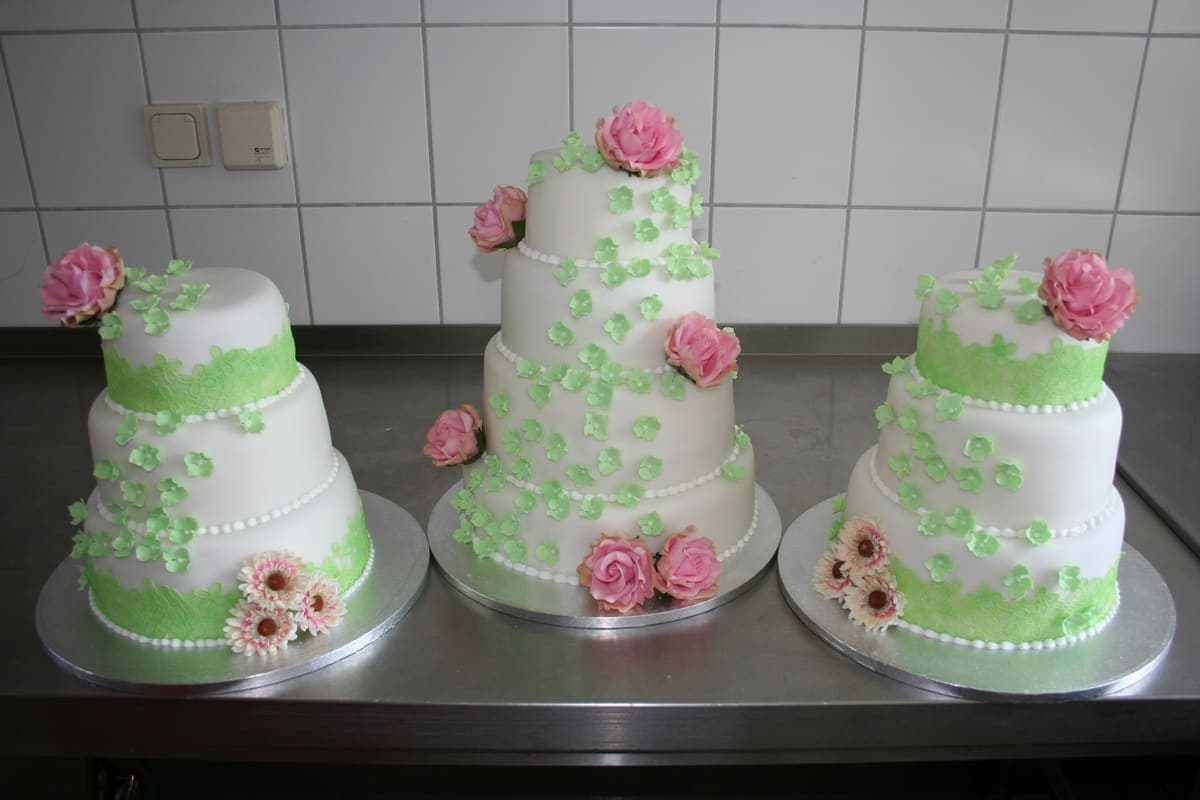 Drei passende Hochzeitstorten in Weiß-Grün mit Blütendekoration
