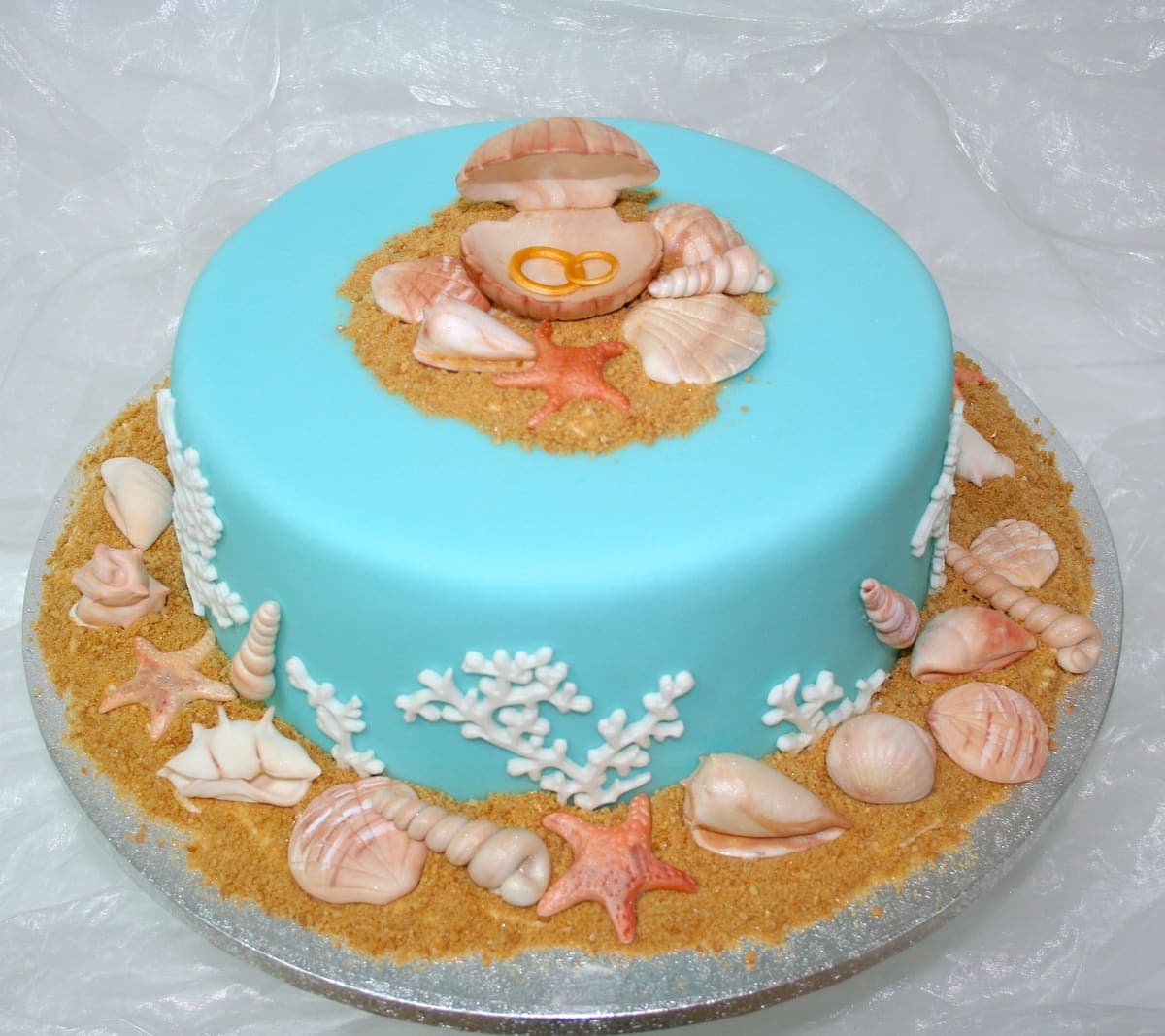 Türkise Torte mit Muscheln, Seesternen und Perle in offener Muschel