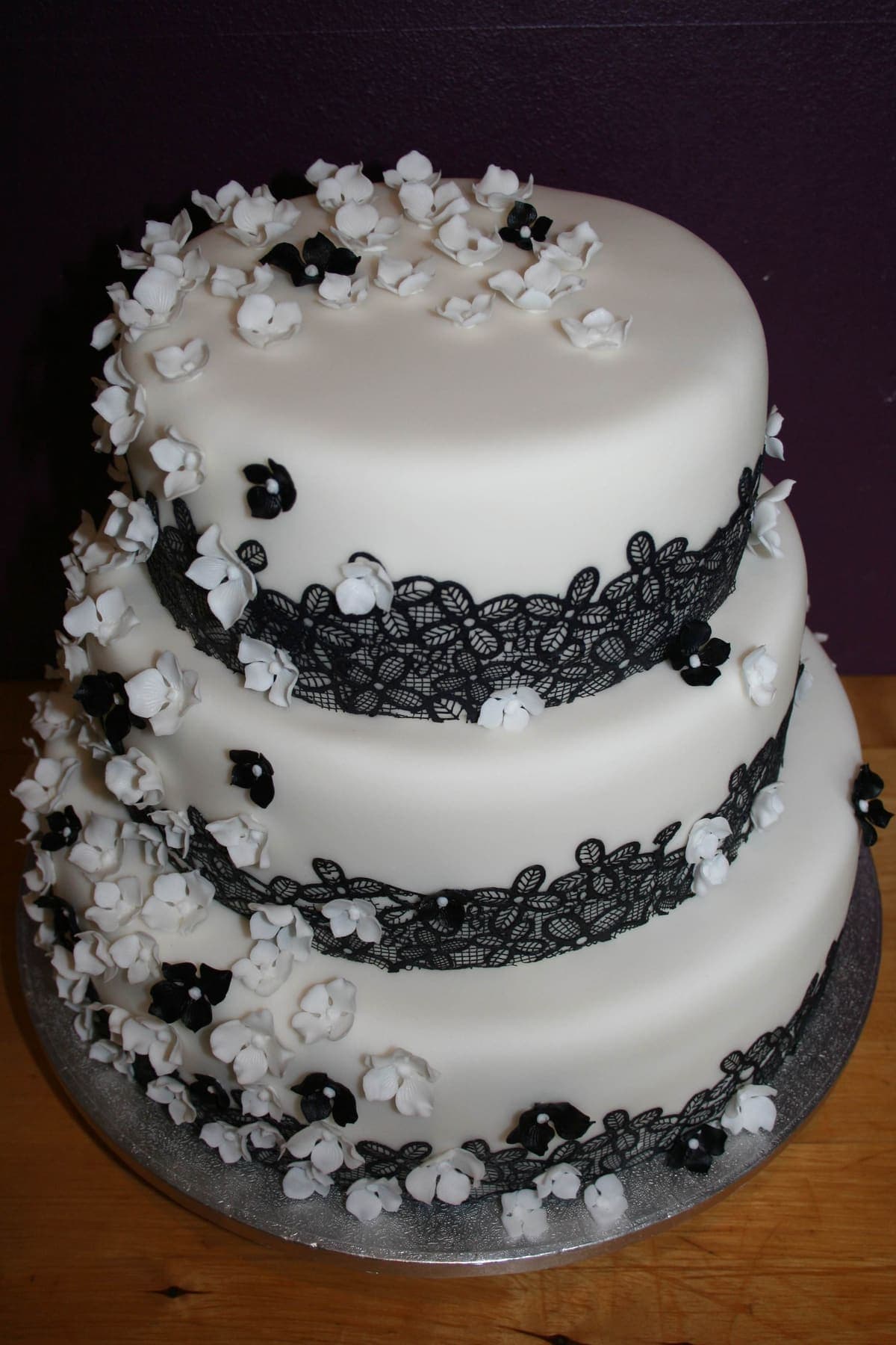 Dreistöckige Hochzeitstorte mit schwarzer Spitze und weißen Blüten für Hochzeiten in Landshut